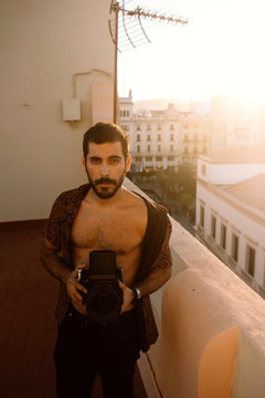 Handsome man taking pictures with an old camera at sunset