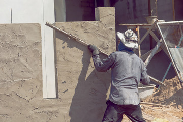 Construction workers plastering building wall using cement plaster