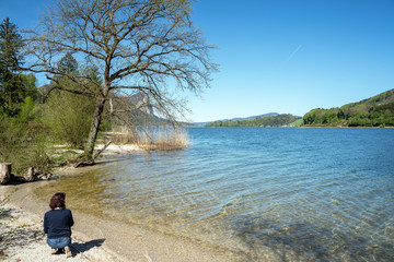 Junge Frau kniet am Ufer eines Sees
