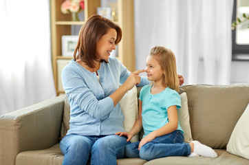 family, generation and people concept - happy smiling mother and daughter sitting on sofa at home