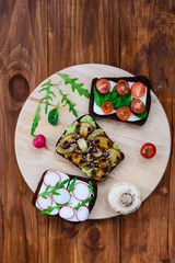 Sandwich set on a wooden board. Sandwiches from radish, avocado, mushrooms, tomatoes, spinach, cheese.