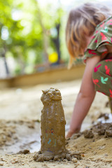 Kleines Kind spielt mit Matsch und Sand. Little girl playing with mud pies and sand.