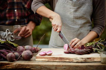 Couple cutting beets on cutting board