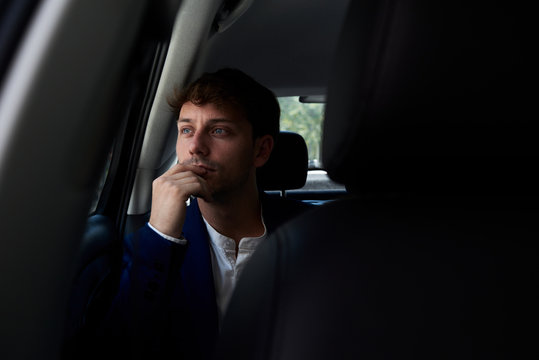 Dark portrait of smart casual businessman inside of taxi.