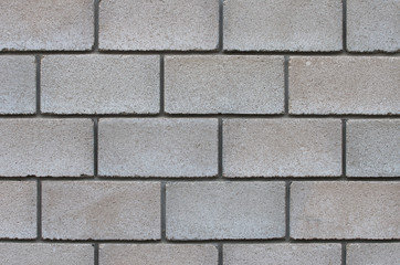 The wall of artificial brick made of concrete chips of gray color, interconnected with cement.