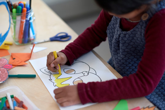Young indian girl colouring a cat mask face