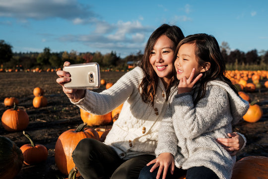 Asian Mother and Daughter Taking Selfie Picture During Pumpkin Patch