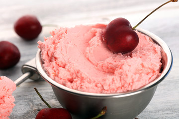 Cherry and vanilla ice cream scoop with fresh cherries and mint on a rustic background