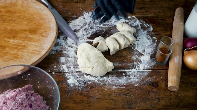 Woman in black gloves makes small balls from the dough for cooking pie with meat
