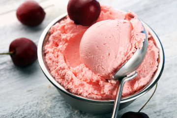Cherry and vanilla ice cream scoop with fresh cherries and mint on a rustic background