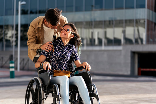 Young woman sitting on a wheelchair and her boyfriend walking