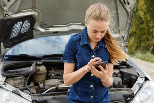 Woman with phone at broken car