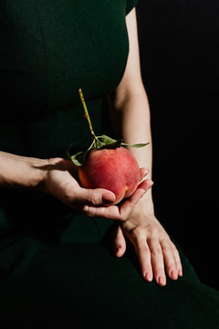 Midsection of woman holding peach