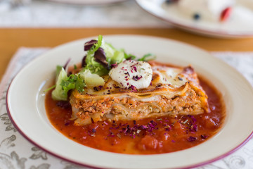 Tasty delicious italian dish lasagna with tomato sauce and cream cheese with green salat. Food, tasty dinner concept