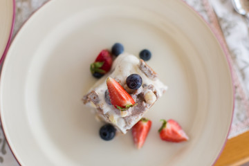 Delicious sugar cold milk dessert on plate in cafe. Ice cream with fresh stawberries, blueberries and chocolate