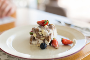 Delicious sugar cold milk dessert on plate in cafe. Ice cream with fresh stawberries, blueberries and chocolate