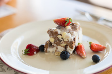 Delicious sugar cold milk dessert on plate in cafe. Ice cream with fresh stawberries, blueberries and chocolate