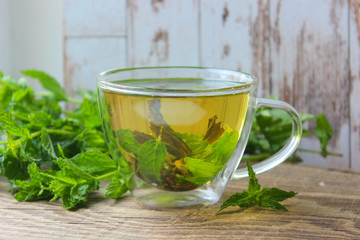 Natural mint tea and fresh mint leaves on wooden rustic background