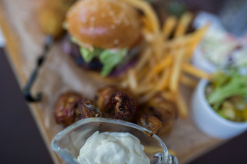 Food plate with fried chicken wings, burger, fried potatoes, sauce, salad, grilled meat . Fast unhealthy tasty food concept