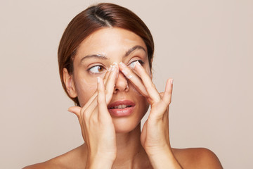 Woman portrait applying cream or moisturiser isolated In studio - skin care hydration closeup