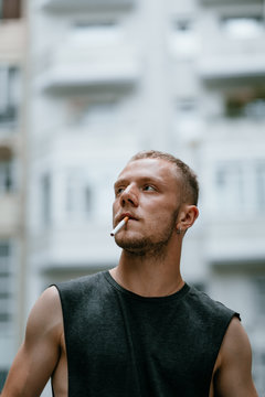 Stylish man smoking surrounded by buildings