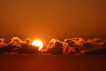 Sunset with dark clouds, setting shining sun and orange sky. Beautiful skyline for background
