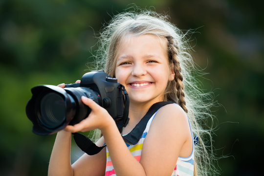 positive female child taking pictures with camera in park