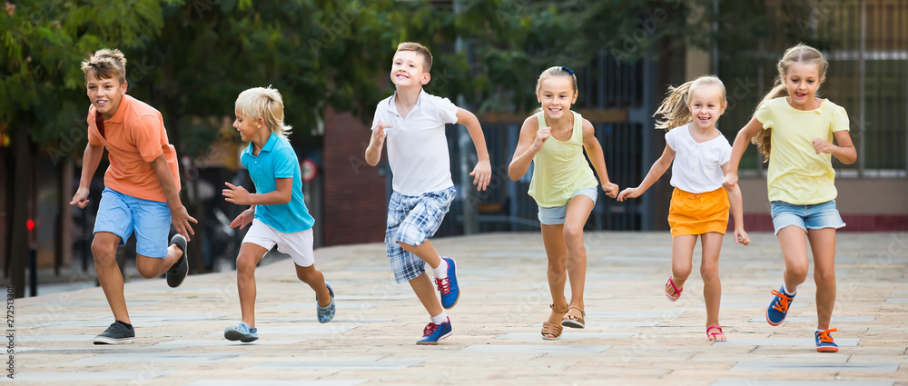 Wall mural kids actively playing and running together on street on summer day