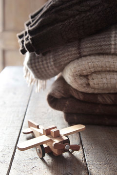 Wooden toy plane with blankets on table