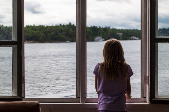Fototapeta Girl looking out of boathouse window