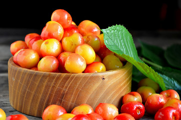 Sweet cherry in a wooden bowl on a wooden table.