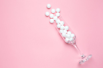 Champagne glass with white balls on pink background minimal style.
