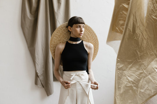 fashion model standing in studio scene with layered fabrics draped and moving in wind