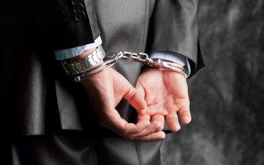Cropped image of male hands in handcuffs behind his back