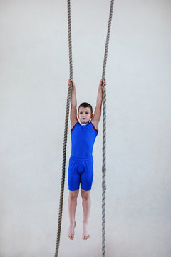 Young boy climbs up the rope