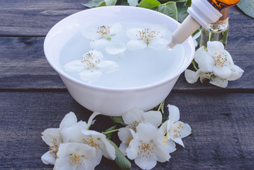 Fototapeta na wymiar Jasmine essential oil and flowers on wooden table background.