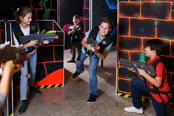 Fototapeta na wymiar Cheery teens aiming laser guns at other players
