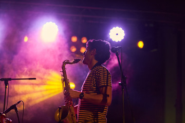Young musician playing saxophone in a live concert