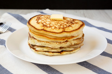 Homemade pancakes with butter on a white plate, side view. Close-up.