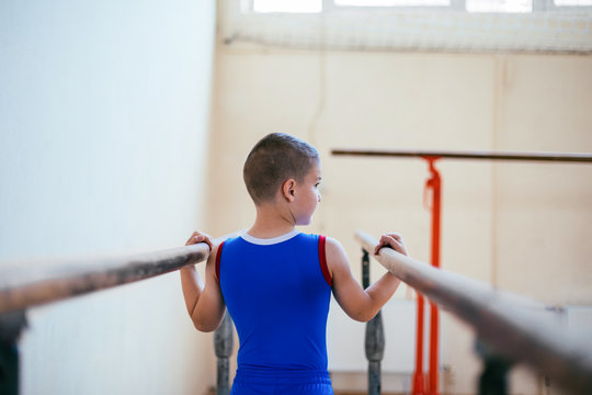 Gymnastics, young boy practicing on parallel bars