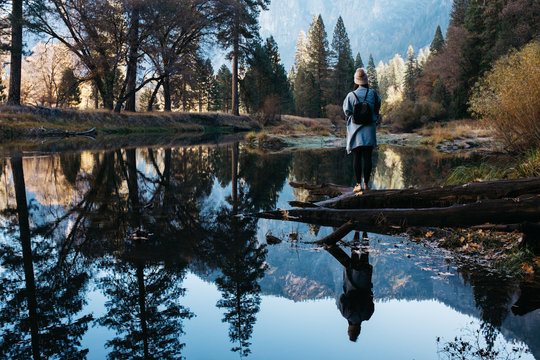 young woman by beautiful reflection lake in fall mountain trees