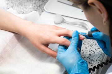 Nail technician giving a customer a manicure at nail salon. Young caucasian woman receiving a...
