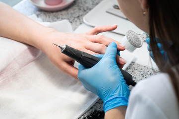 Nail technician giving a customer a manicure at nail salon. Young caucasian woman receiving a manicure. Closeup shot of a woman doing manicure
