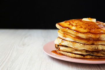 Homemade pancakes with butter and maple syrup on a pink plate, side view. Close-up. Copy space.