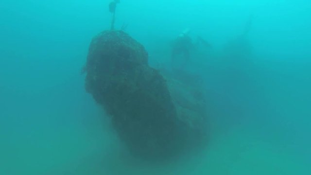 Diving around the bow of an underwater boat shipwreck in the French Polynesia with scuba diver appearing in the background