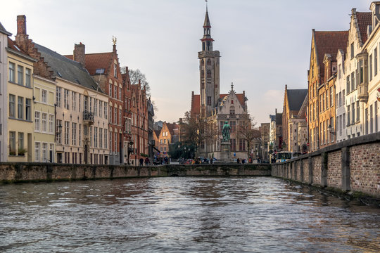 View to Jan van Eyckplein (Jan van Eyck Square) viewed from a nearby canal with Flemish painter Jan van Eyck monument and The Poortersloge (Burgher&rsquo;s Lodge) building.