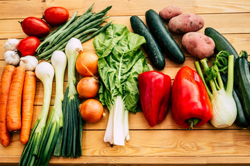 Healthy lifestyle eating all kind of vegetables and not put on weight . Wooden table with assortment of raw vegetables freshly picked from the garden. Full of colors
