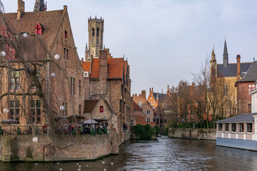 Fototapeta premium The Rozenhoedkaai (Quay of the Rosary) canal in Bruges with the classic medieval buildings and Belfry of Bruges in the background. Quay of Rosary in sunny day.