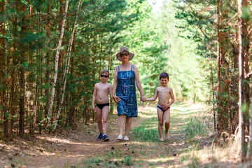 Naklejka na ściany i meble Young grandmother walks in the woods with two grandchildren