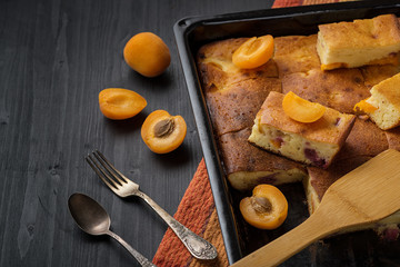 Fruit tart and apricots on a black wooden table.